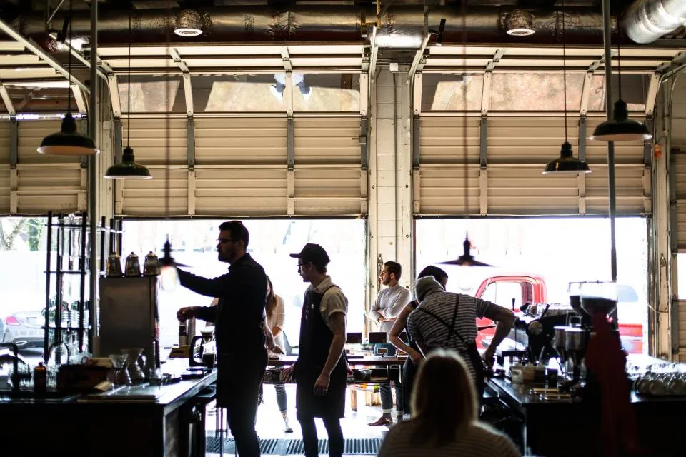 People ordering inside a bright café with its garage doors open