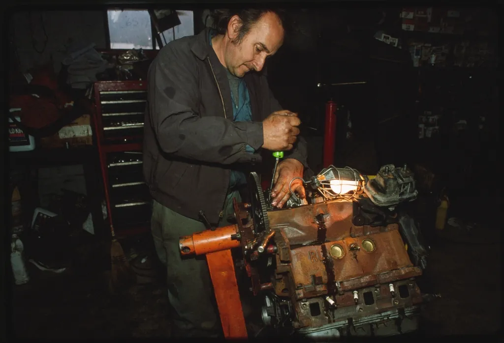 A mechanic rebuilding an engine in a cluttered garage
