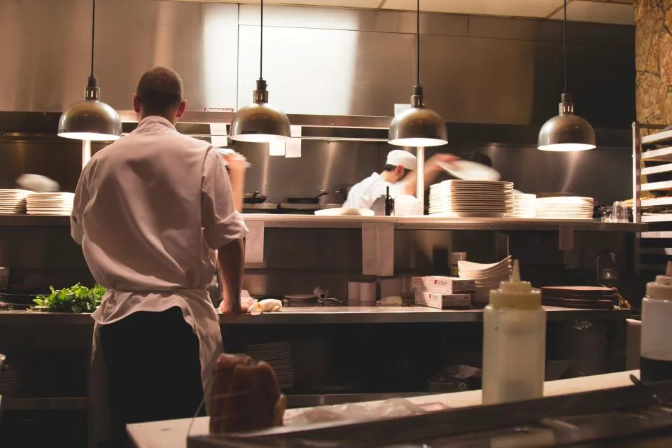A chef at the pass of a busy restaurant kitchen